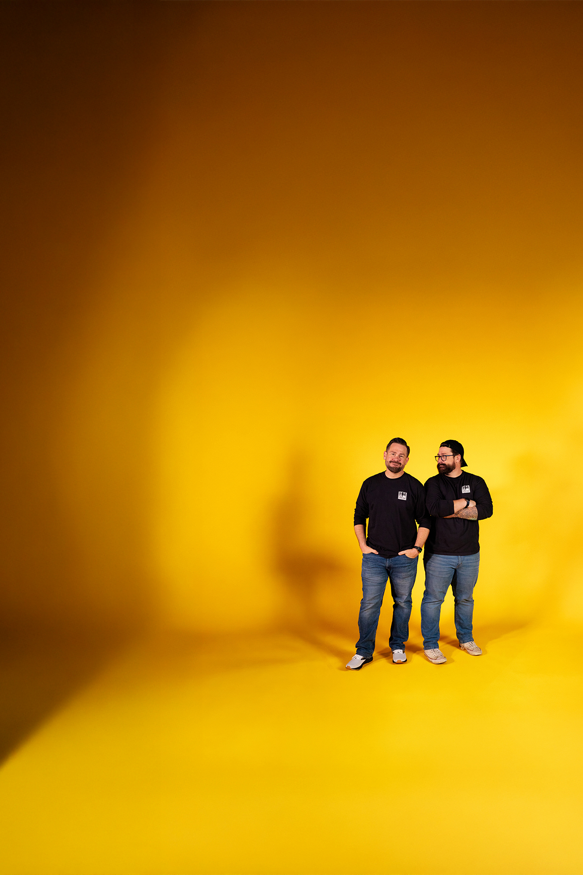 Ben and Luke Garrison standing on a yellow studio backdrop
